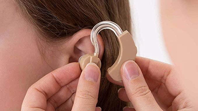 Ultra hearing aid for adults being fitted comfortably behind the ear for improved hearing.